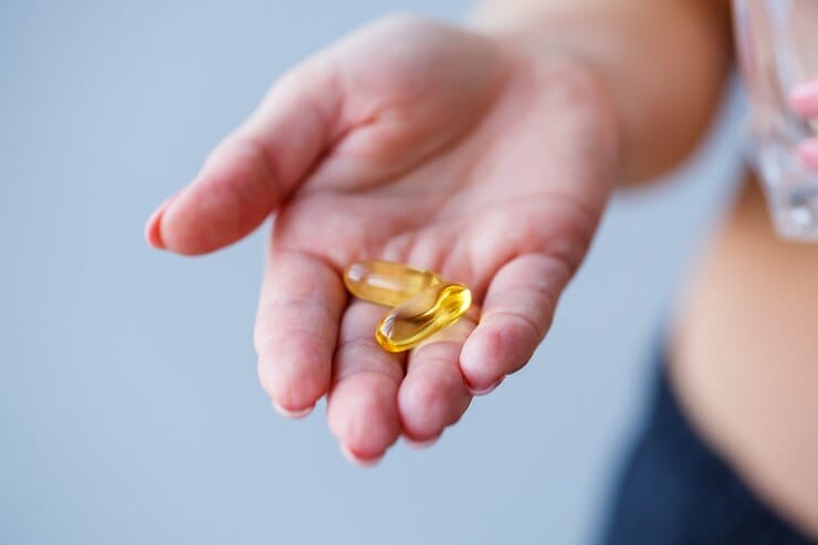 mao com 2 comprimidos de omega 3
