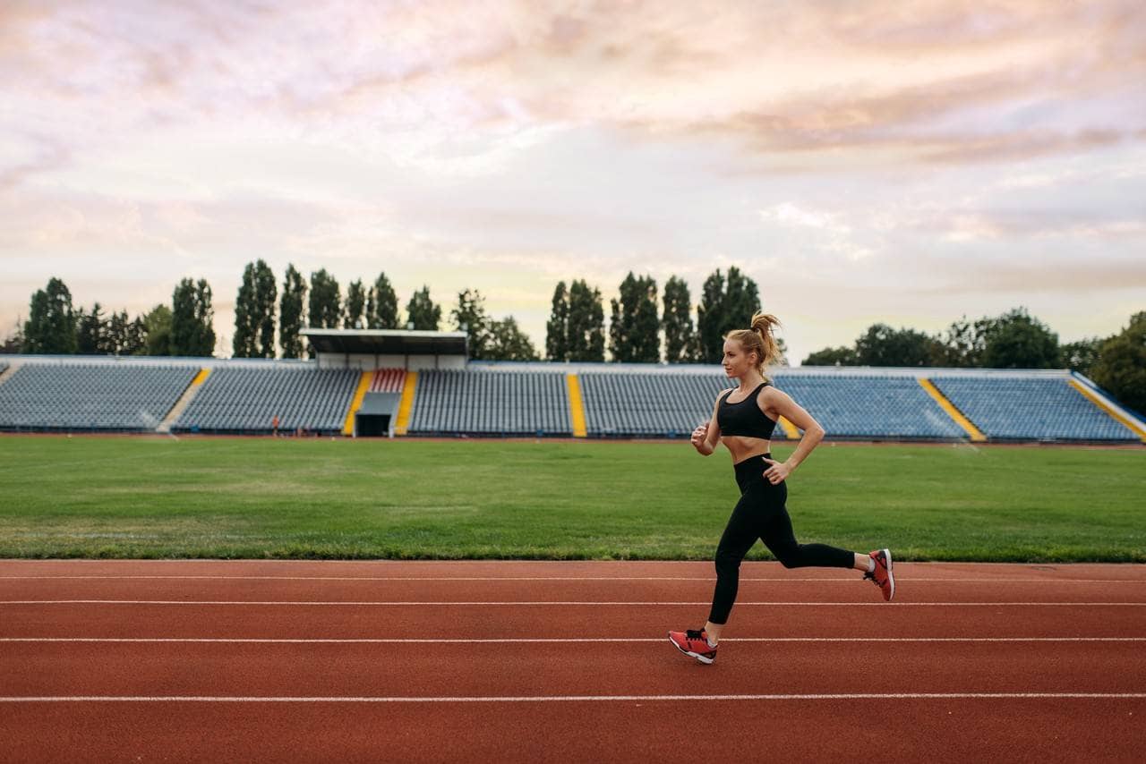 Mulher correndo na pista de atletismo