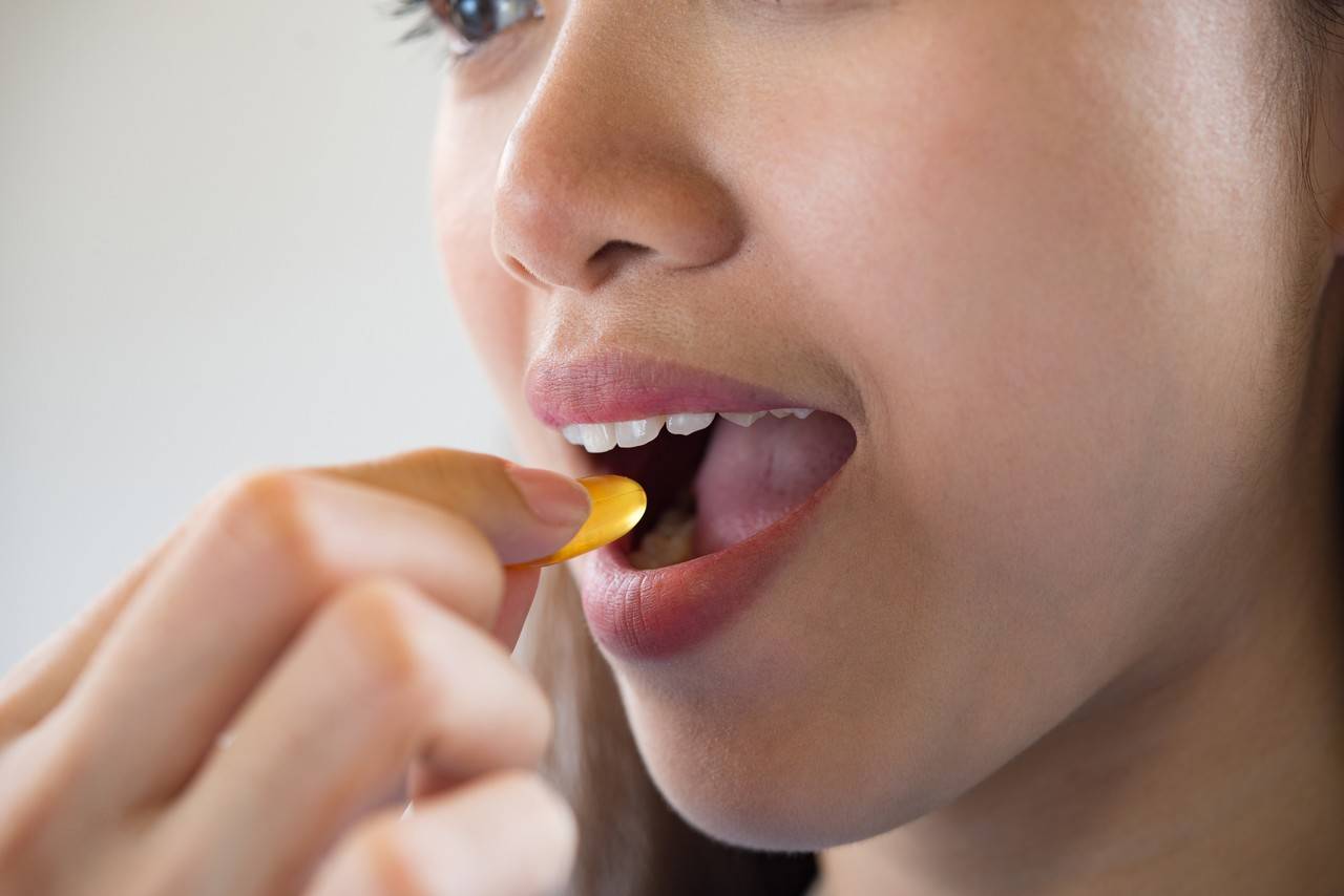 Mulher tomando pilula de omega 3