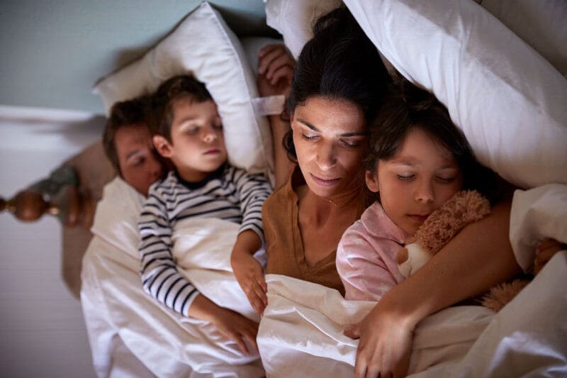 Família dormindo junta em uma cama confortável