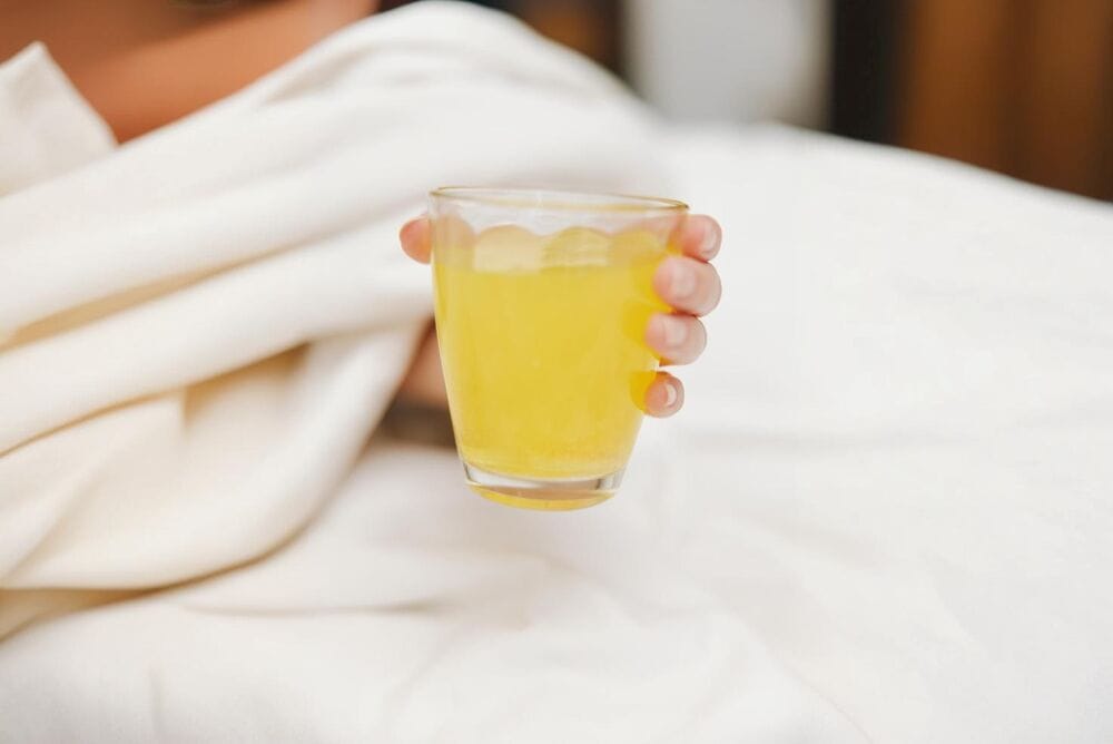 Copo de suco amarelo em uma mão