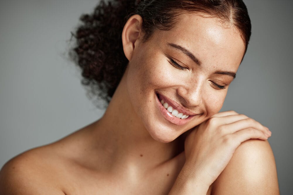 Mulher sorrindo com pele saudável e cabelos cacheados