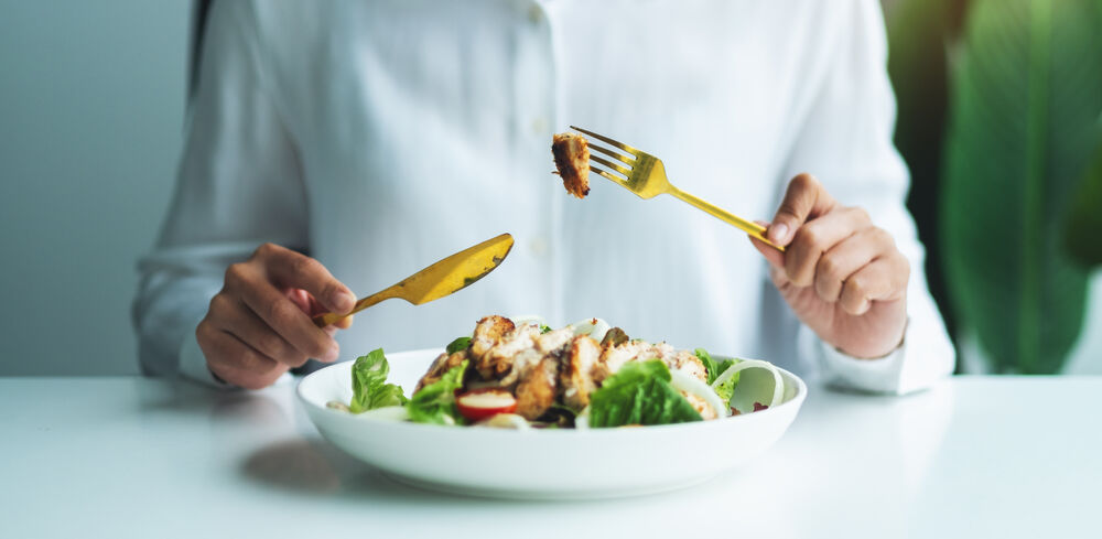 Pessoa comendo salada saudável com frango grelhado