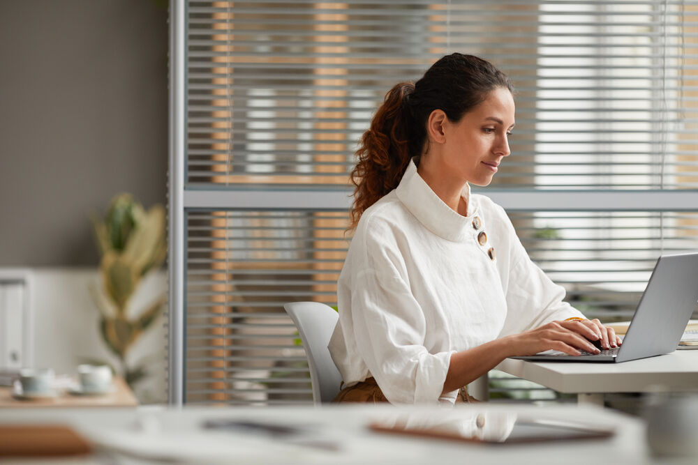 Mulher trabalhando em um laptop em ambiente moderno.