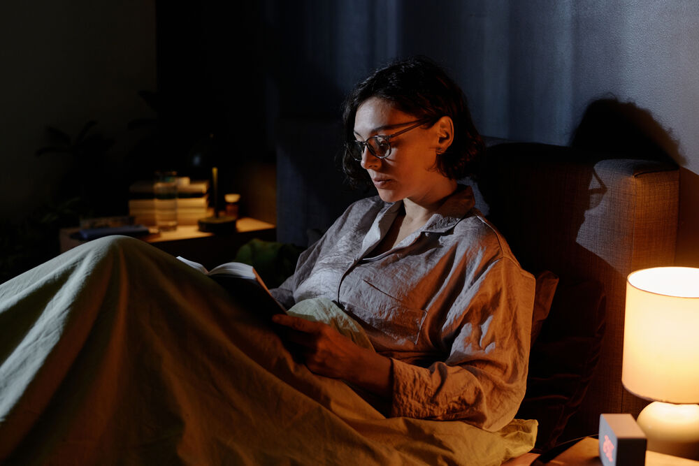 mulher deitada na cama realizando uma leitura