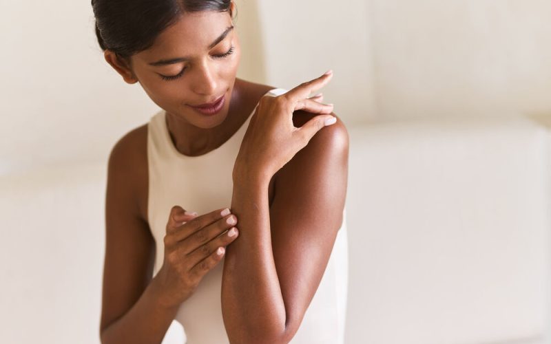 Mulher passando hidratante na pele.