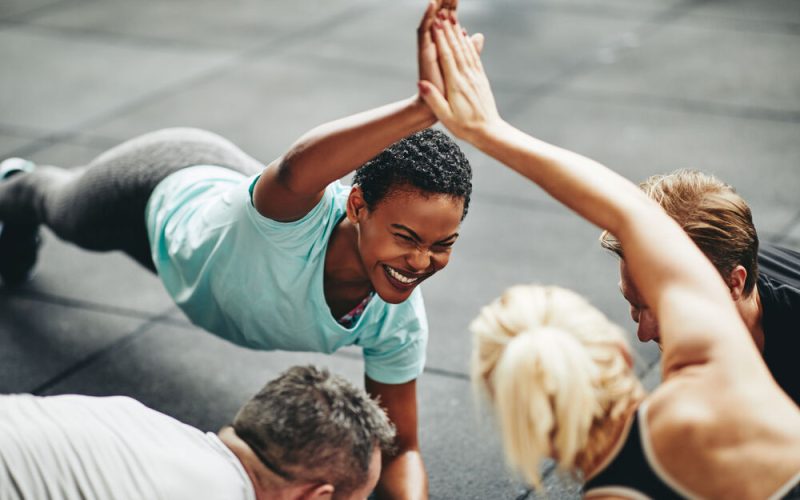 Pessoas se exercitando em grupo com alegria.