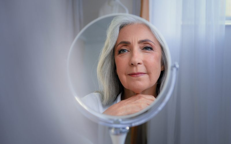 Mirror reflection female wrinkled face 50s middle-aged Caucasian woman senior lady looking self lover skin care grandmother thinking pampering mirrored soft facial beauty cosmetology rejuvenation. High quality 4k footage