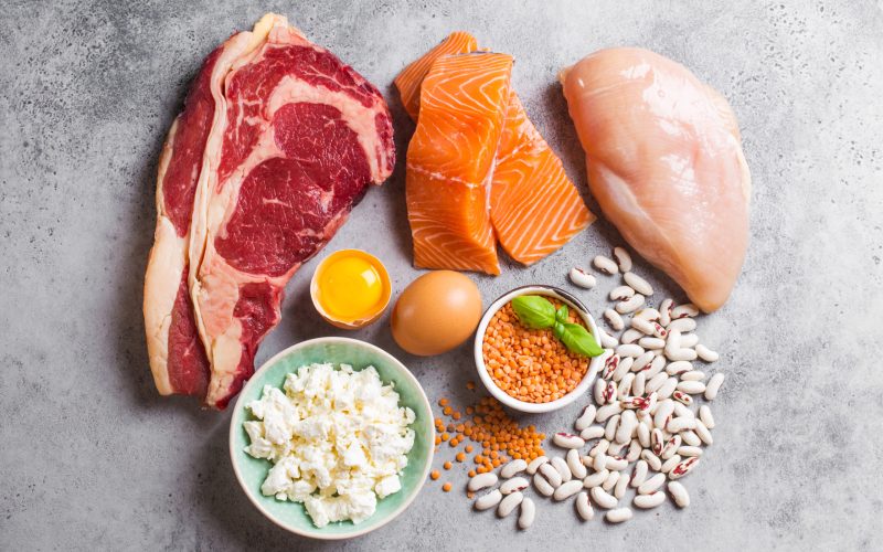 Assortment of natural sources of protein from food: meat, fish, chicken, dairy products, eggs, beans. Diet, healthy eating, wellness, bodybuilding concept, top view, stone background
